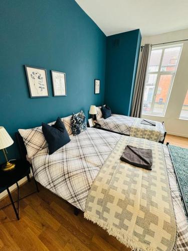 two beds in a room with blue walls at Jubilee Rooms 15 Minutes Central London in London