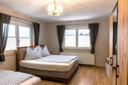 2 Betten in einem Schlafzimmer mit Fenstern und einem Kronleuchter in der Unterkunft Real Top 1 in Keutschach am See