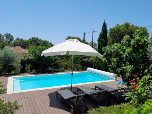 - une piscine avec un parasol, 2 chaises et une table avec un parasol dans l'établissement Maison de vacances dans le verdon, à Saint-Julien
