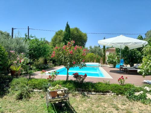 een zwembad in een tuin met een parasol bij Maison de vacances dans le verdon in Saint-Julien