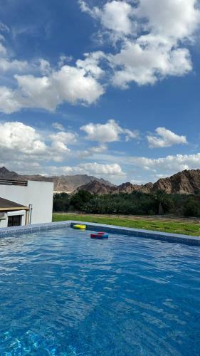 a swimming pool with two kayaks in the water at Alhara Lodge استراحة الحارة 
