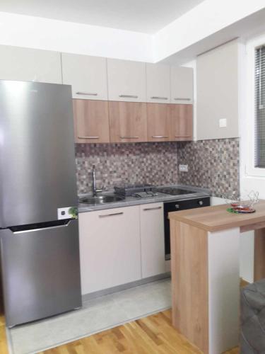 a kitchen with white cabinets and a stainless steel refrigerator at APARTMANS AJAN OHRID in Ohrid