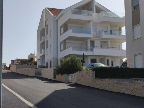 a white apartment building next to a street at Dolphin view with a pool by the beach in Mandre