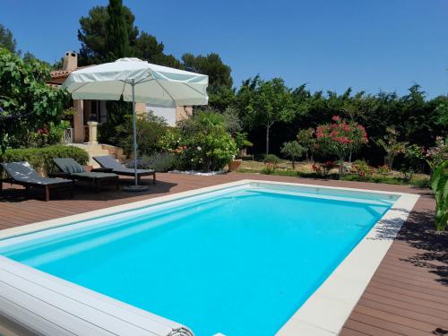 - une piscine avec un parasol à côté d'une maison dans l'établissement Maison de vacances dans le verdon, à Saint-Julien