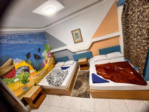 Habitación con 2 camas y una pintura en la pared. en Seaview Hotel Dahab en Dahab