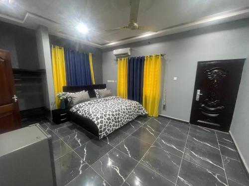 a bedroom with a black and white bed and yellow curtains at Frennin Court in Accra