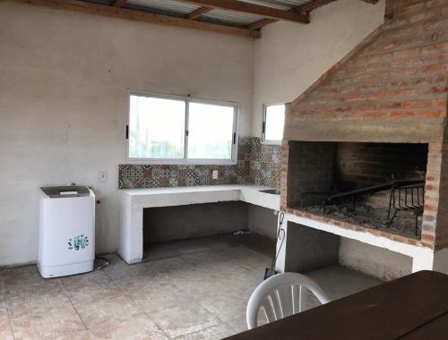 an empty room with a fireplace and a window at Casa de Coral in Punta Del Diablo