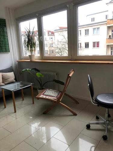 a room with a chair and a table and two windows at Sky view Neukölln in Berlin