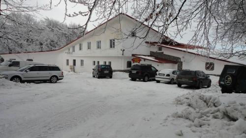 a snow covered yard with cars parked in front of a building at Намира се под връх Исполин,на 5км от Шипка,има 300м ски писта със Чайна и ски гардероб+детски шейни,паркинг, Леглова база-35 места разпределени в 11 стаи,всички стаи са със самостоятелна баня и тоалетна. 