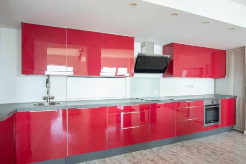 - une cuisine rouge et blanche avec des armoires rouges dans l'établissement Appartement spacieux - Vue mer panoramique, à Villefranche-sur-Mer