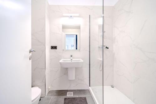 a white bathroom with a sink and a shower at Smart Home - Gloria Apartment by Avenue in Timişoara
