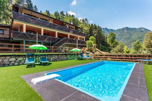 a pool with chairs and umbrellas in front of a building at Apartments in Pieve di Ledro/Ledrosee 22704 in Ledro