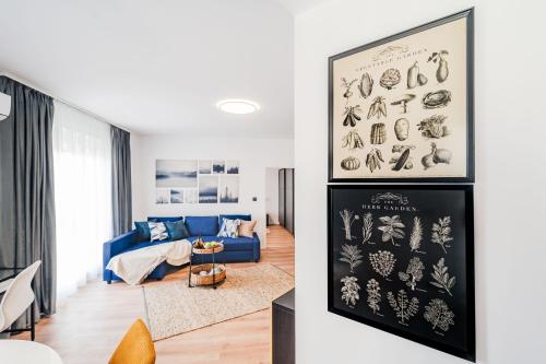 a living room with a blue couch and a painting of vegetables at Smart Home - Gloria Apartment by Avenue in Timişoara