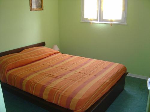 - une chambre verte avec un lit et une couette à rayures d'orange dans l'établissement la golondrina, à Frontignan