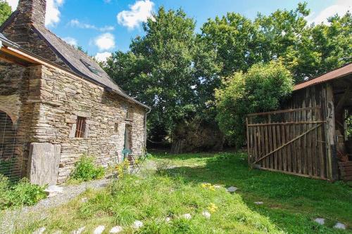 - un vieux bâtiment en pierre avec une porte en bois dans une cour dans l'établissement Longère tinyhouse avec son jardin-forêt, à Saint-Just