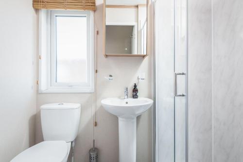 uma casa de banho branca com um WC e um lavatório em Maison Verte Lodge 8 Close to St Andrews em Strathkinness