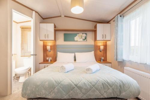 um quarto com uma cama com duas toalhas em Maison Verte Lodge 8 Close to St Andrews em Strathkinness