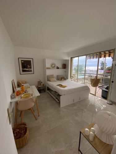 - une chambre blanche avec un lit, une table et un bureau dans l'établissement Studio refait à neuf face mer, à Cannes