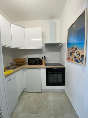 une petite cuisine avec des armoires blanches et un micro-ondes dans l'établissement Studio refait à neuf face mer, à Cannes