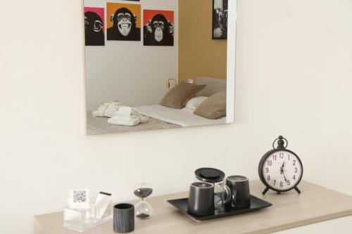 un espejo en una pared sobre una mesa con un reloj en Bed and Breakfast Donna Maria, en Bari