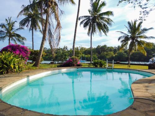 a swimming pool with palm trees in the background at MJ Marina hotel in Mombasa