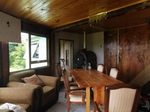 sala de estar con mesa de madera y sofá en CASA CON QUINCHO, en Ancud