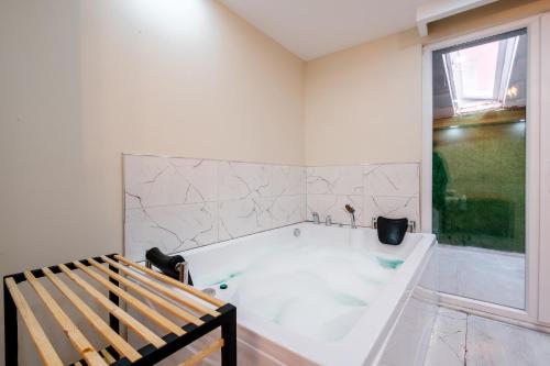 - une baignoire blanche dans une chambre avec un banc dans l'établissement Cozy Residence w Jacuzzi Balcony 5 min to Taksim, à Istanbul