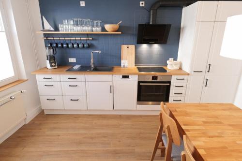 a kitchen with white cabinets and a sink and a table at NEU! Kleine Auszeit - ABC1 -nur Feriengäste! in Wismar