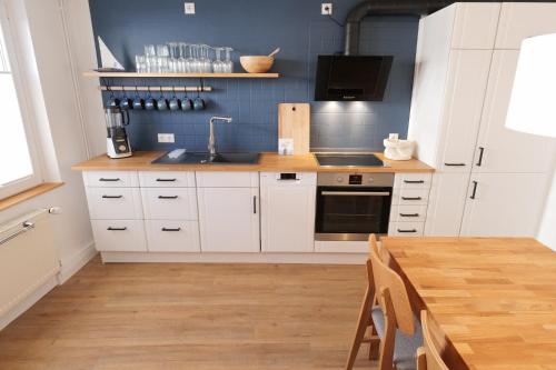 a kitchen with white cabinets and a sink and a table at NEU! Ferienhaus Kleine Auszeit - Nur für Feriengäste - ABC1 in Wismar