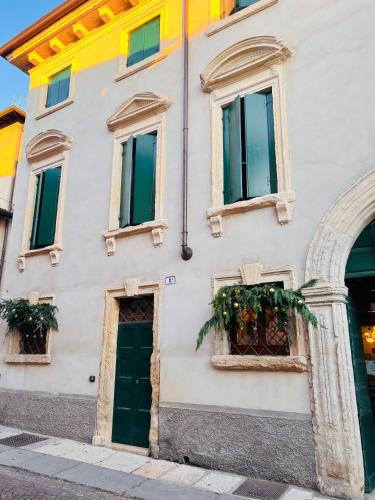 a white building with green doors and windows at Pietra di Verona Residenza in Verona