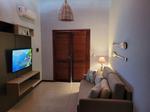 een woonkamer met een bank en een flatscreen-tv bij Flat Kite Blue in Pipa