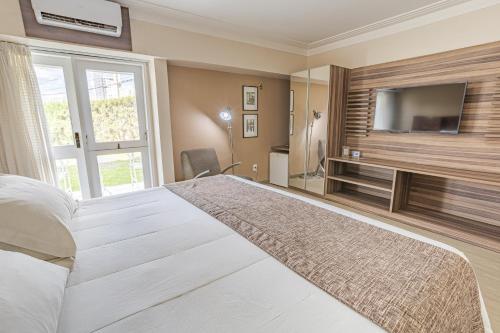 a bedroom with a large bed with a flat screen tv at Hotel Village Premium Campina Grande in Campina Grande