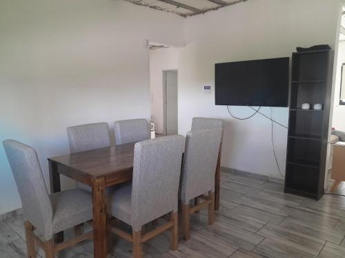 a dining room with a table and chairs and a flat screen tv at Alquiler temporario villa allende in Córdoba