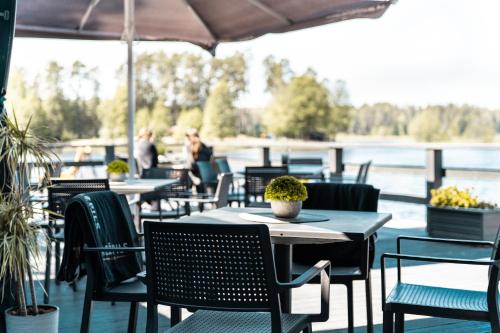 a patio with tables and chairs with a view of the water at Kempings Bejas in Babīte