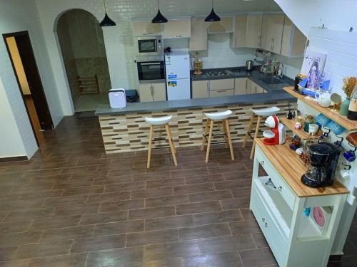 a large kitchen with a counter and stools in it at شاليه لارا in Rayyis