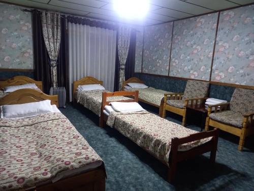 een kamer met drie bedden en stoelen erin bij ХОСТЕЛ FRIENDS in Karakol