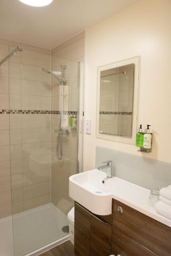 a white bathroom with a sink and a shower at The Black Horse Inn in Maidstone