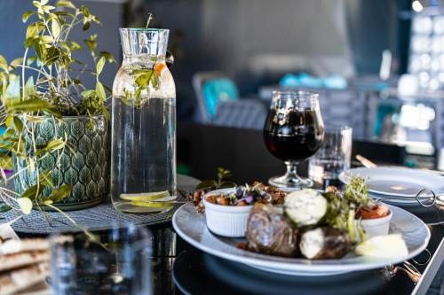 a table with a plate of food and a glass of wine at Kempings Bejas in Babīte