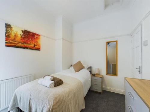 a white bedroom with two beds and a mirror at Cozy Hull House near City Centre - Walkable to the Deep in Hull