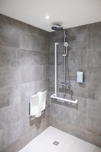 a bathroom with a shower and a tile wall at Campanile Limoges Centre - Gare in Limoges