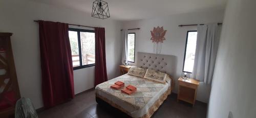 a bedroom with a bed and two windows at Gemas Apart in Villa Yacanto