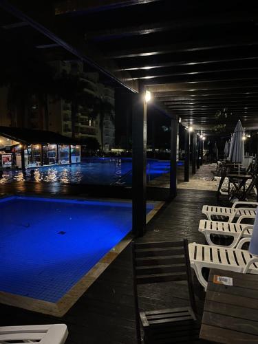 a swimming pool at night with chairs and lights at Vista inesquecível para o mar homeclub BetoCarrero in Penha