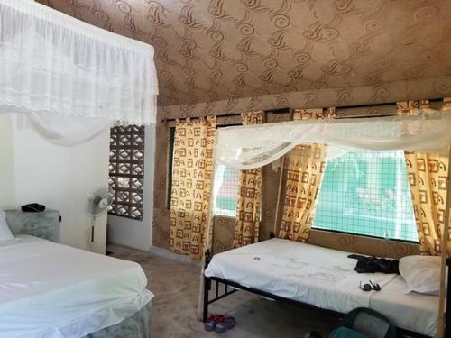 een slaapkamer met 2 bedden en een raam bij The Nyerere Selous Ngalawa Tented Camp in Kwangwazi