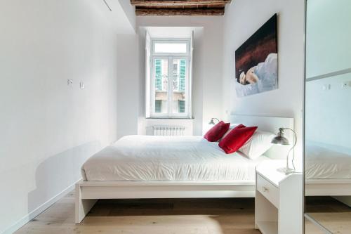 una camera bianca con letto bianco e cuscini rossi di Suite JOIVY BV 66 a Como