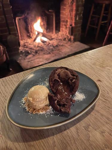 a chocolate cookie and ice cream on a plate in front of a fireplace at The Black Horse Inn in Maidstone