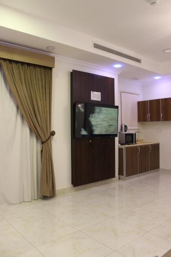 دانة الشرقية للشقق المخدومة بالدمام Danat Al Sharqiah Serviced Apartments في الدمام: غرفة بها تلفزيون بشاشة مسطحة وستارة