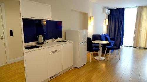 Lux Apart Hotel 555 في باتومي: مطبخ مع ثلاجة وطاولة وكراسي