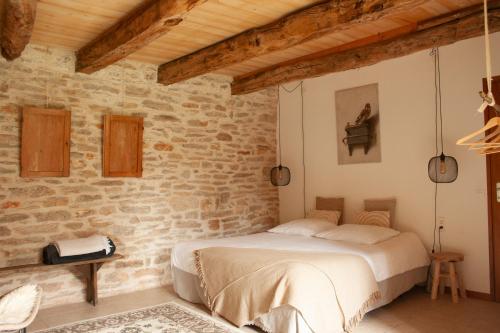 ein Schlafzimmer mit einem Bett in einer Ziegelwand in der Unterkunft Chambres d'hôtes Pech Blanc in Calvignac
