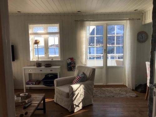 a living room with a chair and two windows at Utsiktsperle på Reine I Lofoten in Reine