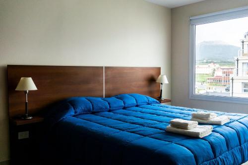niebieskie łóżko w sypialni z dużym oknem w obiekcie Gente del Sur - Antartida w mieście Ushuaia